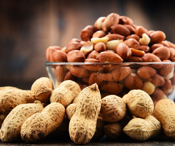 Bowl with peanuts on wooden table. Delicacies