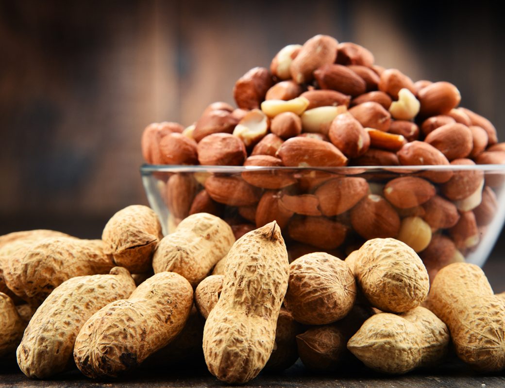 Bowl with peanuts on wooden table. Delicacies