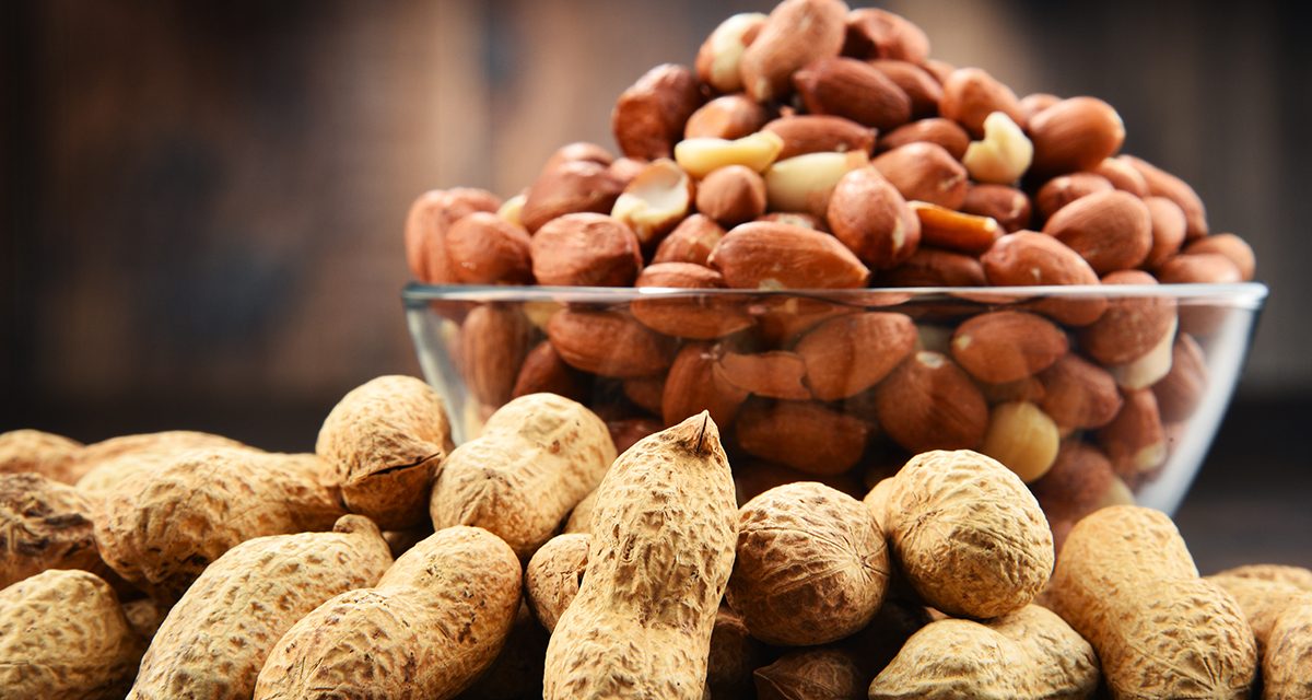 Bowl with peanuts on wooden table. Delicacies