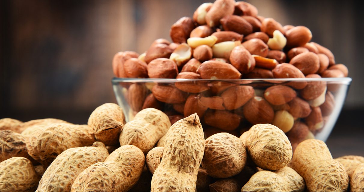Bowl with peanuts on wooden table. Delicacies