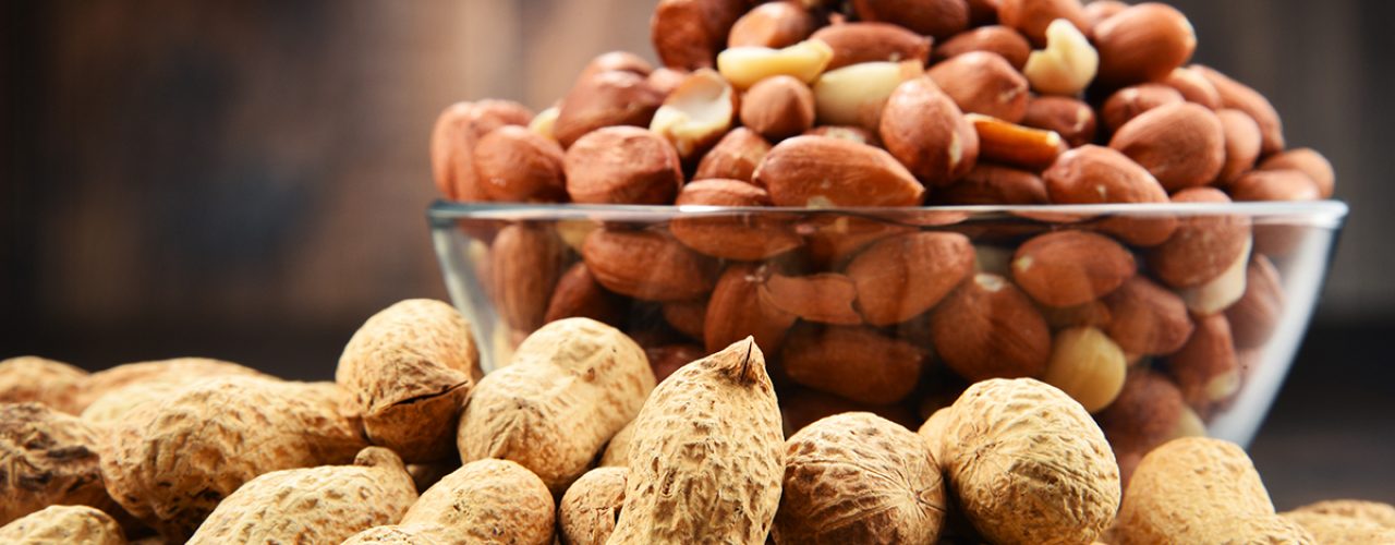 Bowl with peanuts on wooden table. Delicacies