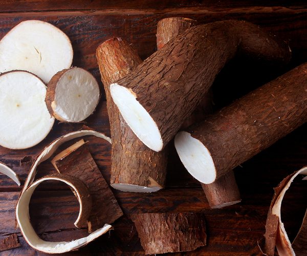 fresh cassava and peels and slices on rustic wooden table. Top view