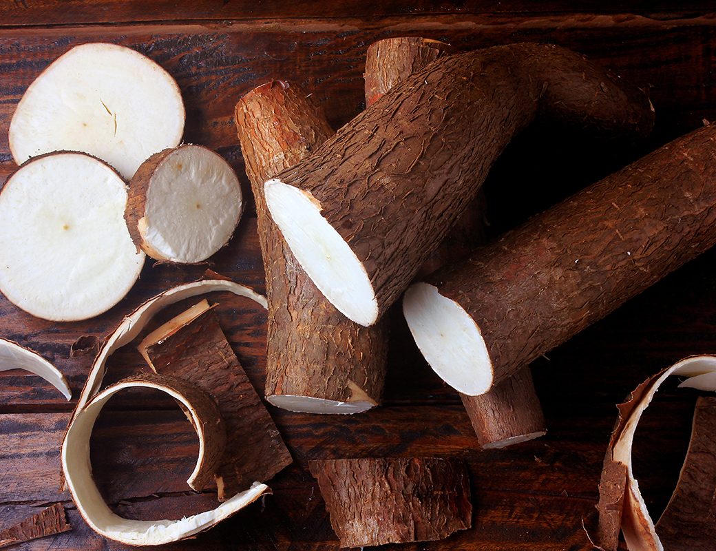 fresh cassava and peels and slices on rustic wooden table. Top view