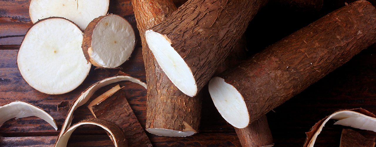 fresh cassava and peels and slices on rustic wooden table. Top view