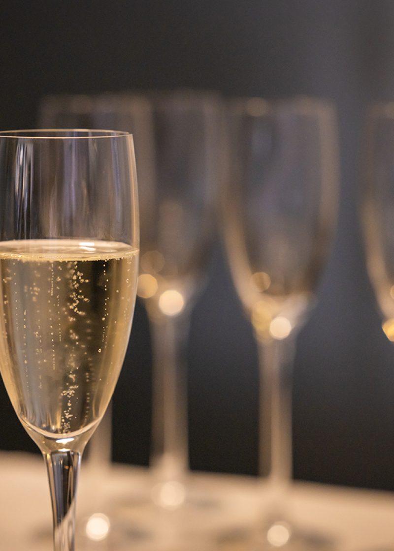 Close-up with glass of champagne and blurred background with other glasses.