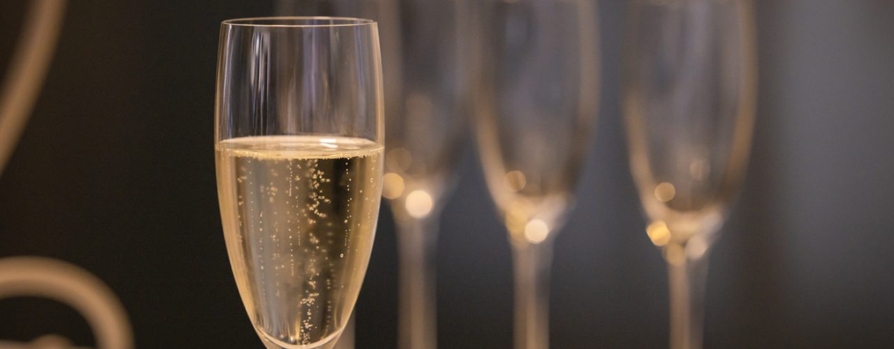 Close-up with glass of champagne and blurred background with other glasses.
